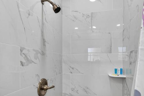 een badkamer met een douche en witte marmeren tegels bij Belleview Gulf Unit 395 in Clearwater Beach