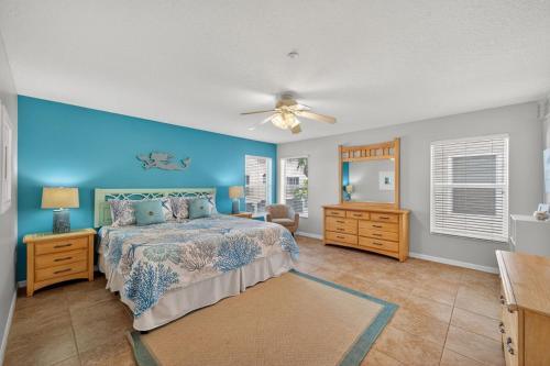 a bedroom with a bed and a blue wall at Captains Cove Unit 402 in Clearwater Beach