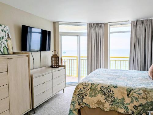 a bedroom with a bed with a television and a balcony at Beautiful Beachfront 2BR2Bath & 2 Balconies in North Myrtle Beach