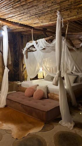 a bedroom with a canopy bed with white drapes at wellgaya ecovillas in Villa Flor