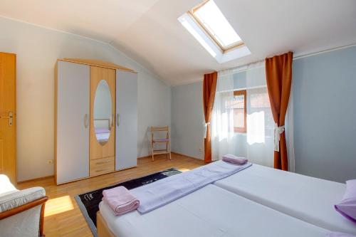 a bedroom with a large white bed and a window at Apartment Palma in Mali Lošinj