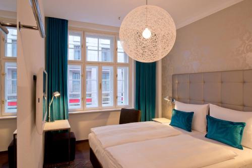 Un dormitorio con una cama grande y una lámpara de araña. en Motel One Wien-Staatsoper, en Viena