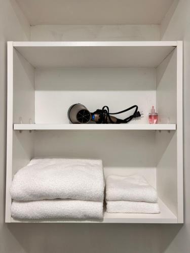 a white shelf with towels and glasses on it at Sandy's Sweet Home in Coquitlam