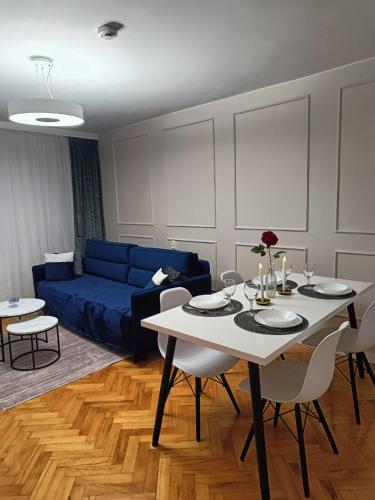 a living room with a table and a blue couch at Apartament Aksamitny in Toruń
