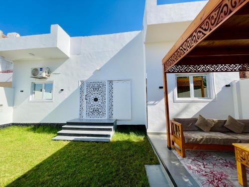 una casa blanca con un sofá y césped en Quiet Villa, en Luxor