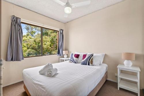 una camera da letto con un grande letto bianco con una finestra di Beachside Retreat with Resort Pool & Spa Access Sandcastles 224 a Coffs Harbour