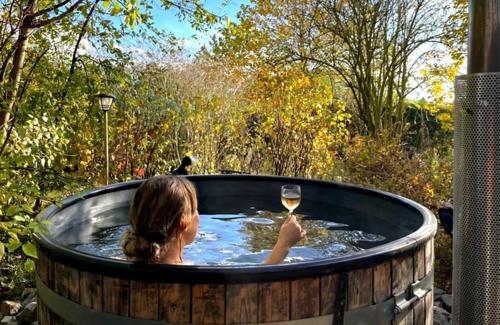 a woman holding a glass of wine in a hot tub at Hanami - tuinkamer in Zwalm