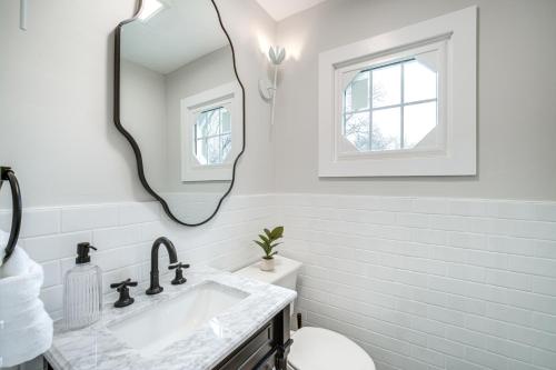 a white bathroom with a sink and a mirror at Explore Cleveland Attractions! Family-Focused Home in Beachwood