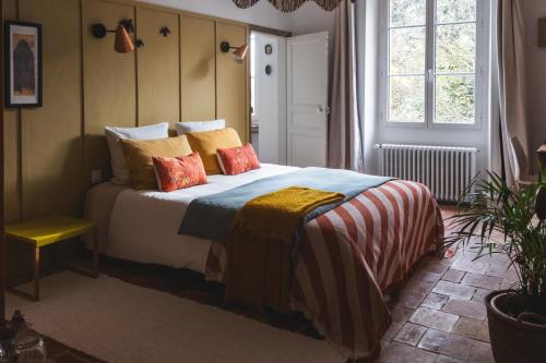 a bedroom with a bed with colorful pillows at Maison d'hôtes La bien-Aimée in Montrevault