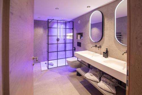 a bathroom with a sink and a toilet and two mirrors at Hotel Wiese in Sankt Leonhard im Pitztal