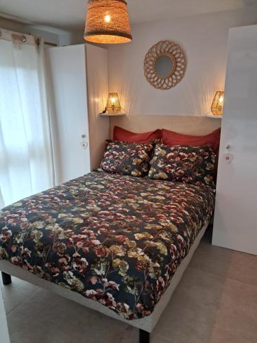 een slaapkamer met een bed met een bloemenbed bij Le Patio du bourg - Studio entre lac et océan in Biscarrosse