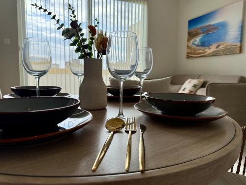 Una mesa de madera con platos y copas de vino encima. en AS3 - The Alley Suites Apartment in Gudja, en Gudja