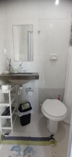 a white bathroom with a toilet and a sink at LAR DE PRAIA - Suíte in Serra