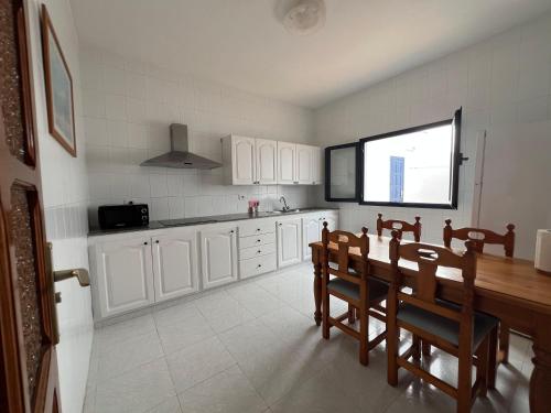 eine Küche mit weißen Schränken und einem Tisch und Stühlen in der Unterkunft casa el lajiar in Orzola