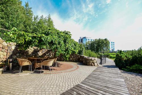 a patio with a table and chairs next to a stone wall at Vila Ambasada in Šventoji