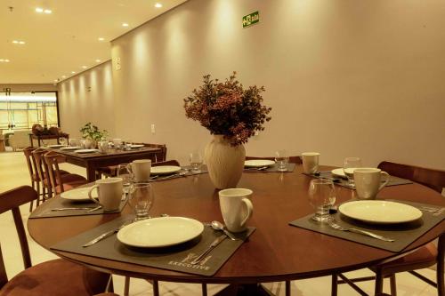 a table with plates and a vase of flowers on it at Bristol Castanhal Hotel in Castanhal