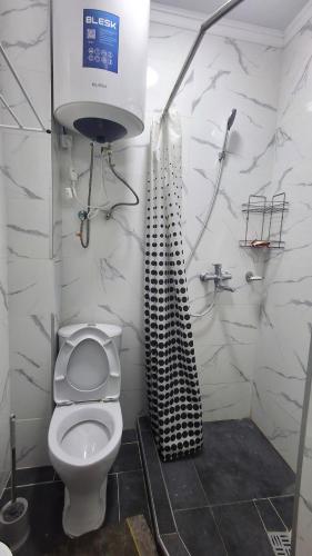 ein Badezimmer mit weißer Toilette und Dusche in der Unterkunft AI Hostel in Bischkek