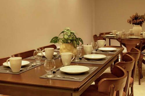 a table with plates and glasses and a plant on it at Bristol Castanhal Hotel in Castanhal