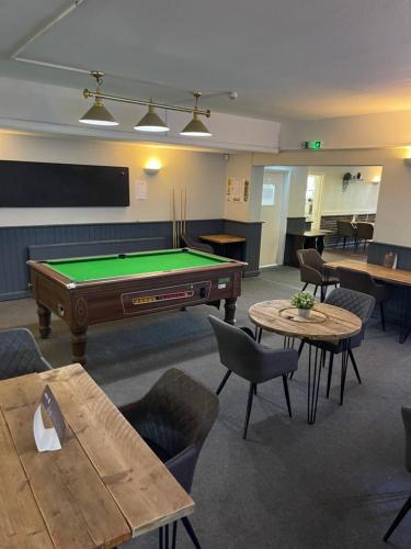Habitación con mesa de billar, mesas y sillas en The Pheasant Inn, en Dunstable
