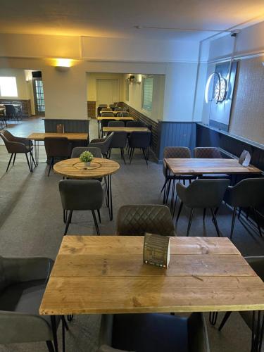 Un comedor con mesas y sillas y un escritorio. en The Pheasant Inn, en Dunstable