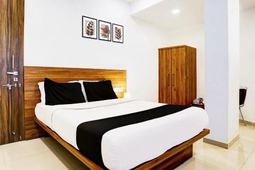 a bedroom with a large bed with a wooden headboard at Super Hotel O Nashik Road Formerly The Address Hotel in Nashik