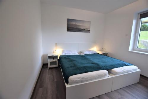 ein weißes Schlafzimmer mit einem Bett mit einer blauen Decke in der Unterkunft Hohes Ufer Sandburg in Hohwacht