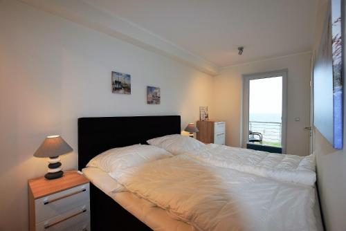 a bedroom with a large white bed with a window at Meeresblick "Seepferdchen" Haus 3 WE 42 in Hohwacht