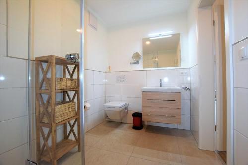 a bathroom with a sink and a toilet and a mirror at Meeresblick "Seepferdchen" Haus 3 WE 42 in Hohwacht