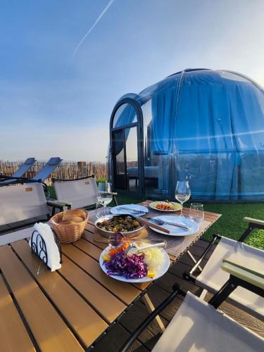 a picnic table with plates of food and a bus at Sky Dome - Alushllari's Farm in Pogradec