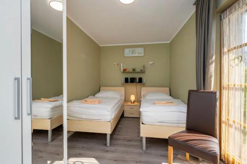 a room with two beds and a chair and a mirror at Ferienpark Freesenbruch Wohnung 4 3 - Inseltreff in Zingst