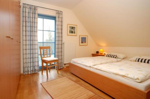 ein Schlafzimmer mit zwei Betten, einem Stuhl und einem Fenster in der Unterkunft Ferienpark Freesenbruch Doppelhaushälfte 12 - Sommerlust in Zingst