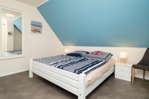 ein Schlafzimmer mit einem Bett, einem Stuhl und einem Spiegel in der Unterkunft Ferienpark Freesenbruch Doppelhaushälfte 11a - Schwalbennest in Zingst