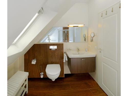 a bathroom with a toilet and a sink under a staircase at Neue Reihe 28 - Wohnung Vogelnest in Zingst