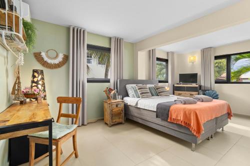 a bedroom with a bed and a desk and windows at Oasis guesthouse, Boutique Style Hotel in Kralendijk