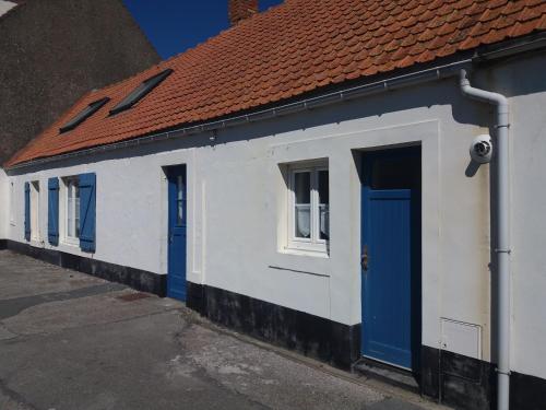 a white building with blue doors and a red roof at Villa Audresselles in Ambleteuse