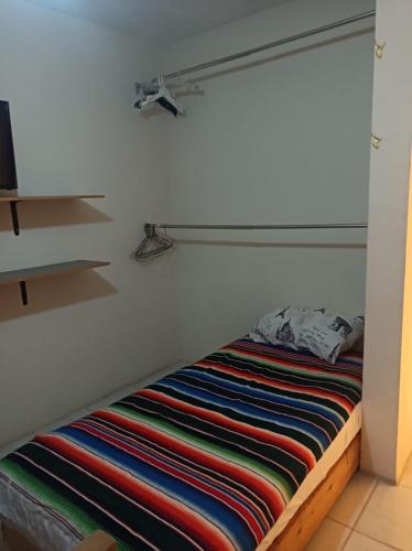 a bed in a room with a shelf at Airport Hostel in Ciudad Juárez