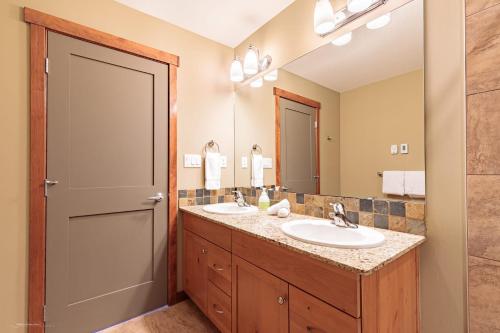 a bathroom with two sinks and a large mirror at El Paraiso - Luxury Downtown Penthouse in Canmore