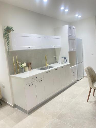 a white kitchen with a sink and a refrigerator at סוויטת האחד והיחידה in Or ‘Aqīvāh
