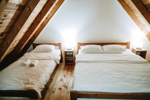 Dos camas en una habitación con sábanas y almohadas blancas. en VM Apartments Zabljak, en Razvršje