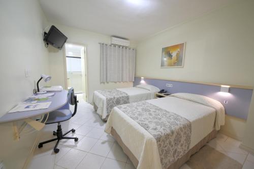 ein Krankenzimmer mit zwei Betten und einem Schreibtisch in der Unterkunft Asppen Hotel in Chapecó