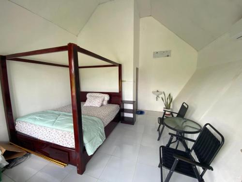Djojo Bungalow في Timbanglawang: غرفة نوم بسرير مظلة وطاولة وكرسي