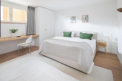 a white bedroom with a large bed and a desk at Strandhaus Südwesthörn in Norderney