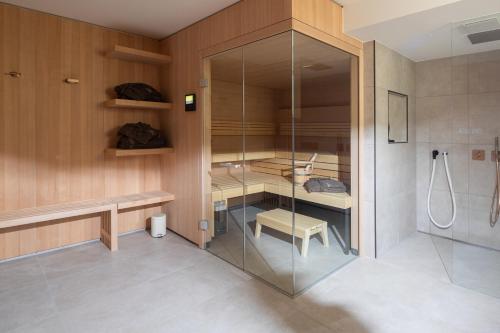 a bathroom with a glass shower and a bench and a stool at Strandhaus Südwesthörn in Norderney