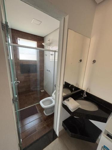 a bathroom with a toilet and a glass shower at Chalés Vale da Roça in Capitólio