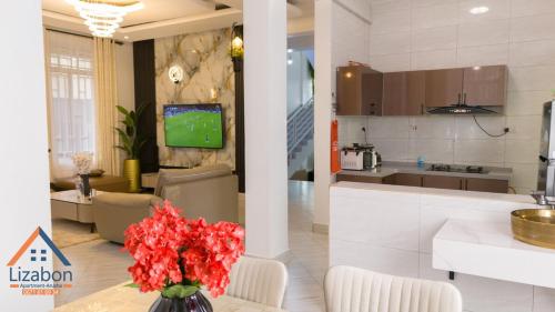 een keuken en woonkamer met rode bloemen in een vaas bij Lizabon Apartment Arusha in Nkoanrua