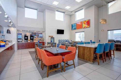 a restaurant with tables and chairs and a cafeteria at Holiday Inn Express & Suites Lantana by IHG in Lantana