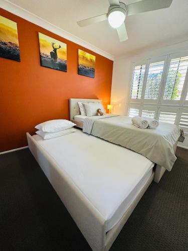 two beds in a room with an orange wall at Southern Sky Villa in Ingleburn