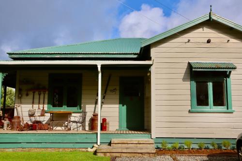 Tongariro Cottage - Hot Tub - Bring Your Dog! في Raurimu: منزل أبيض صغير ذو سقف أخضر