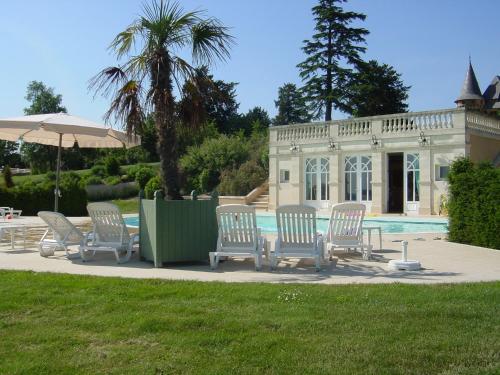 a group of chairs and an umbrella next to a pool at Domaine d'Essendiéras in Saint-Médard-dʼExcideuil