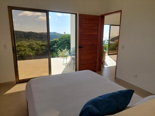 una camera da letto con un letto e una grande finestra di vetro di Villa BotaNICA guest house a San Juan del Sur